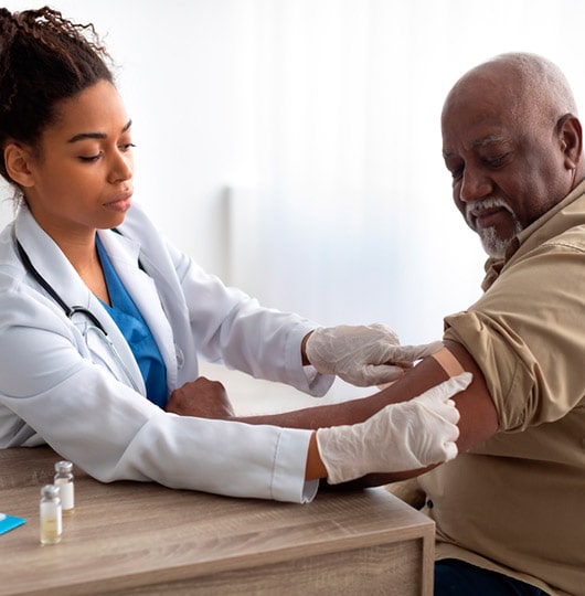 Infectious disease 2 Female doctor placing a bandaid on a male patient’s arm after a vaccination.