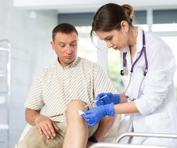 Knee Injections Young,Female,Doctor,Performs,Intra-articular,Injection,Treatment,Of,Knee,Bursitis