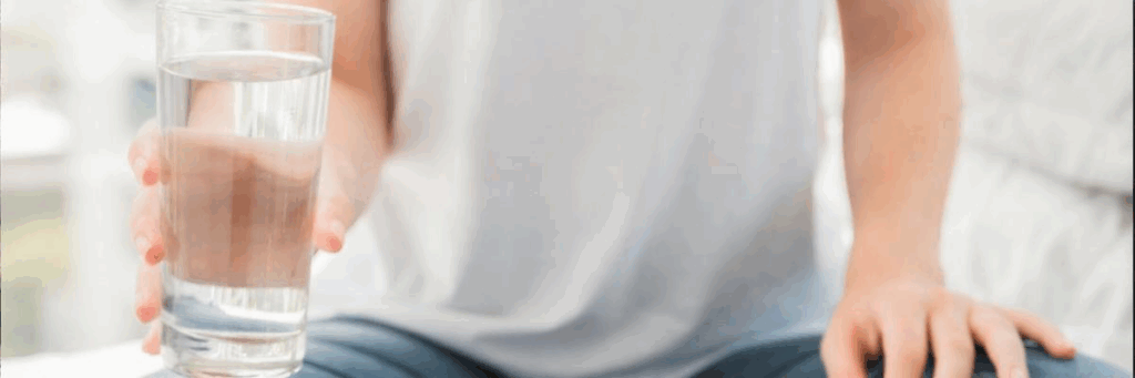 A glass of water and a water bottle on a table, symbolizing proper hydration for kidney and urinary health.